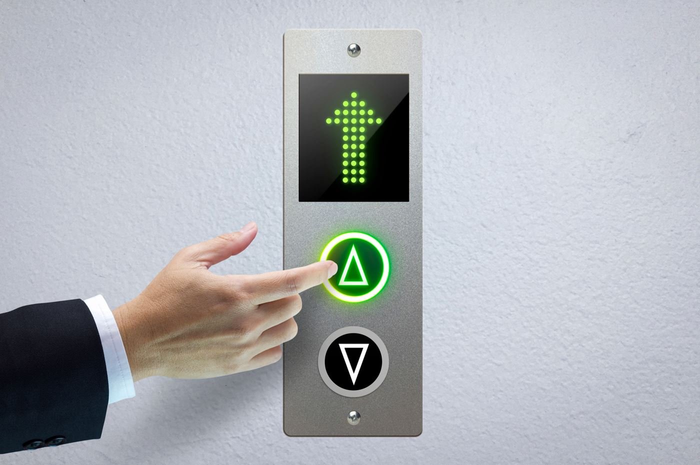 Main appuyant sur un bouton d’appel d’ascenseur lumineux